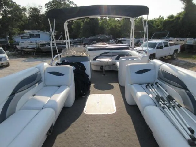 Slide: The Image of 2009 JC 26' Tritoon boat with spacious seating and canopy, parked outdoors. - 5