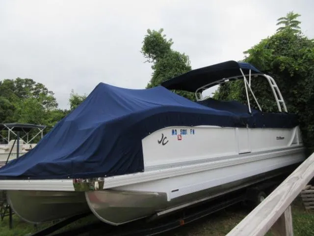 Slide: The Image of 2009 JC 26' Tritoon boat with 300Hp Evinrude outboard, covered and docked outdoors. - 7