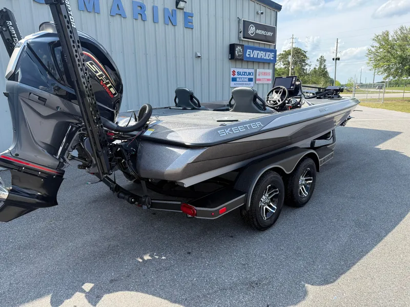 Slide: The Image of 2025 Skeeter ZXR20 boat with dual motors on a trailer, parked outside a marine shop. - 12