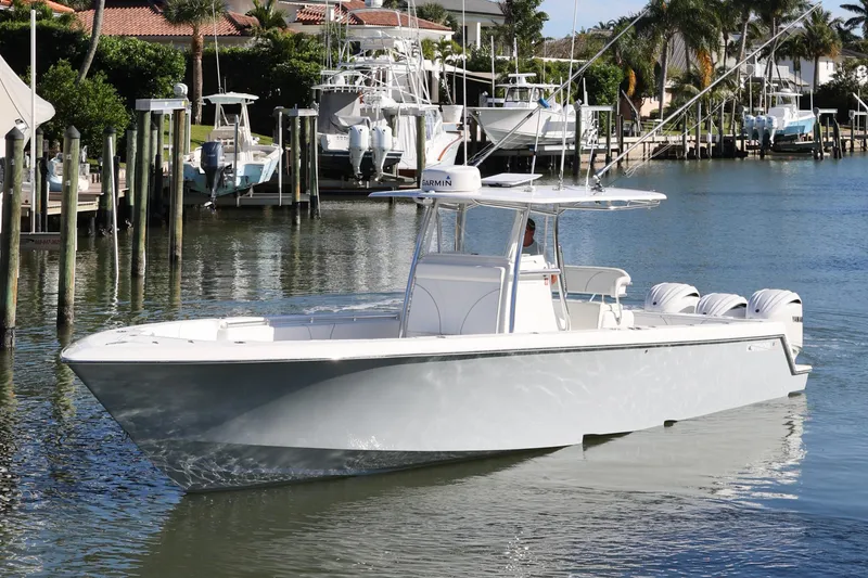 The Image of 2022 Contender 39 ST boat cruising in a marina with palm trees and docks. - 1