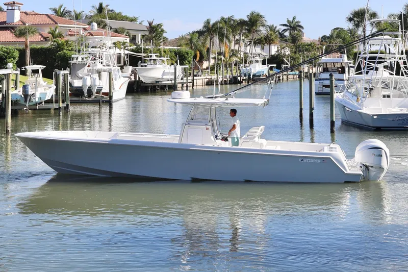 Slide: The Image of 2022 Contender 39 ST boat cruising in a marina with palm trees and docks. - 2