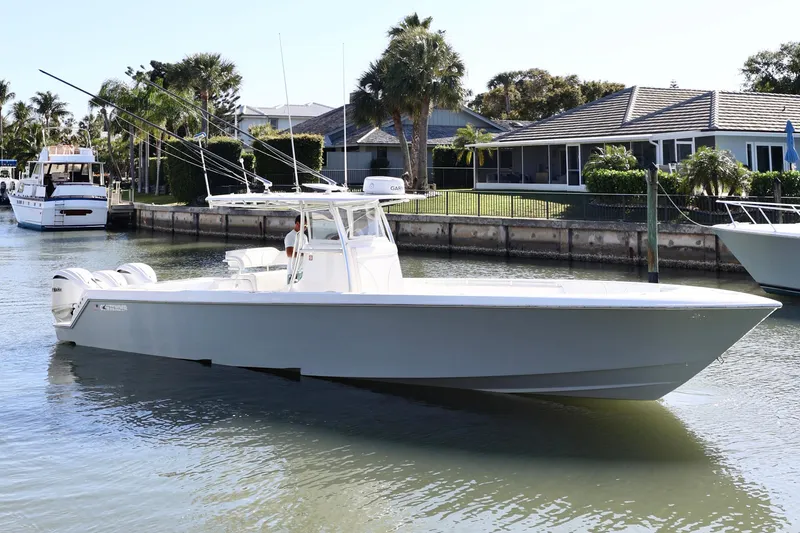 Slide: The Image of 2022 Contender 39 ST boat cruising in a residential canal with palm trees. - 3