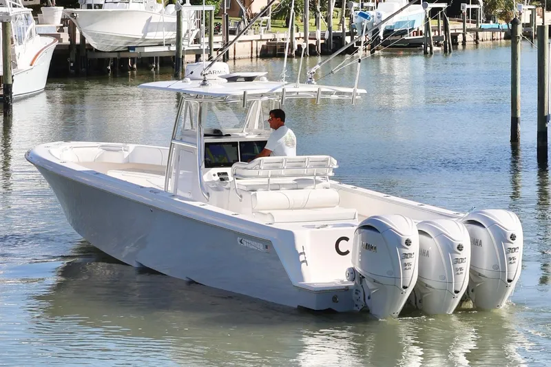 Slide: The Image of 2022 Contender 39 ST boat with triple outboard engines in a marina setting. - 4