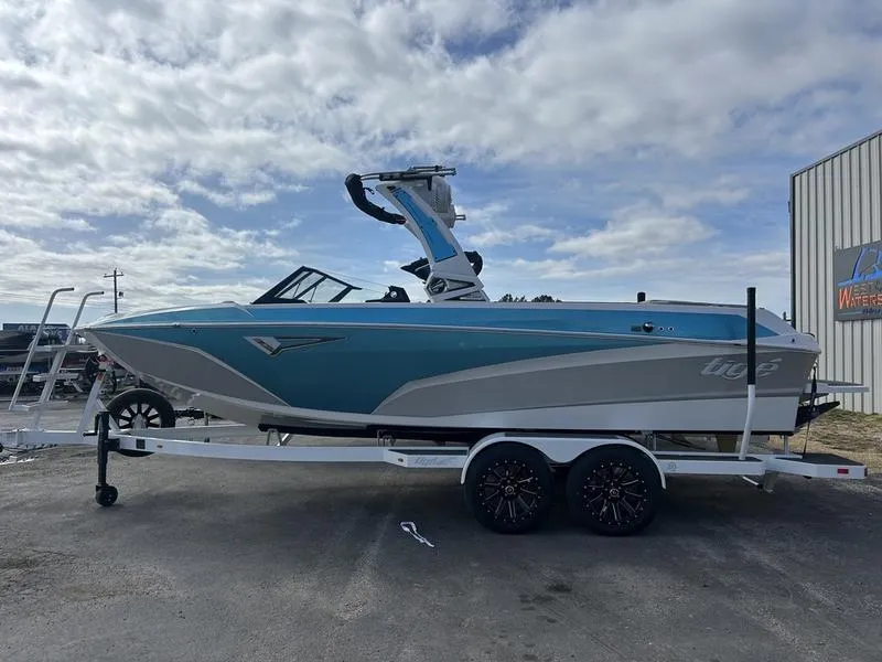 Slide: The Image of 2025 Tigé Z3 boat on trailer, blue and white design, parked outdoors. - 1