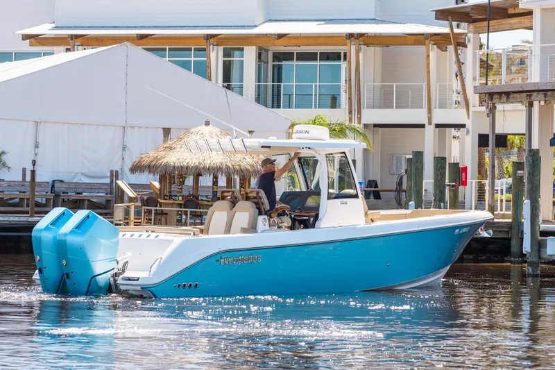 Slide: The Image of 2024 Everglades 315CC boat in marina, featuring blue hull and dual engines. - 0