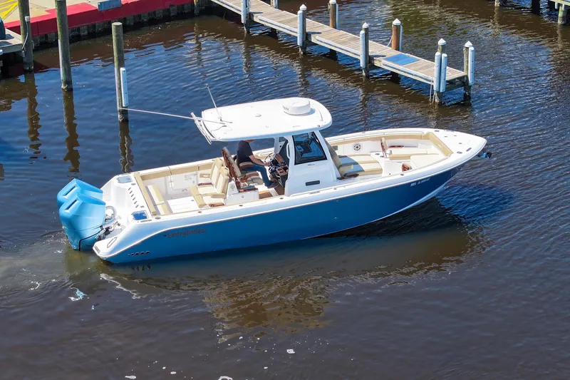 Slide: The Image of 2024 Everglades 315CC boat docked on calm water, featuring a sleek blue and white design. - 15