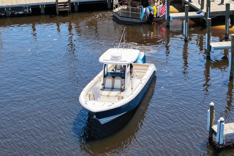 Slide: The Image of 2024 Everglades 315CC boat navigating a marina, surrounded by docks and calm water. - 16