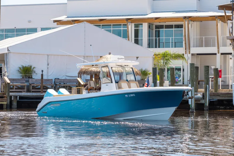 Slide: The Image of 2024 Everglades 315CC boat docked near modern waterfront building. - 2