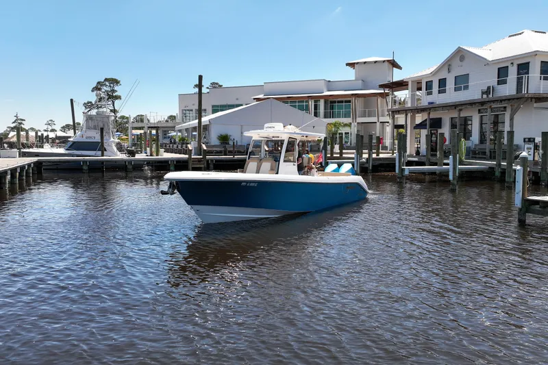 Slide: The Image of 2024 Everglades 315CC boat docked at a marina under clear blue skies. - 25