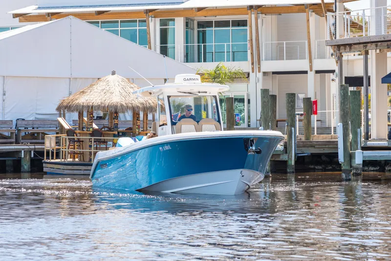 Slide: The Image of 2024 Everglades 315CC boat cruising near waterfront buildings. - 3