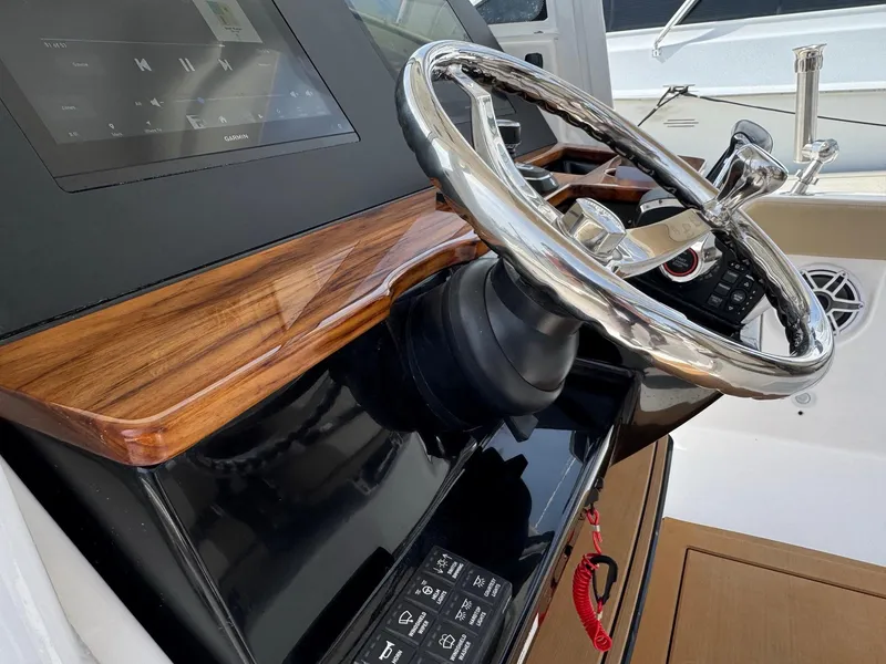 Slide: The Image of 2024 Everglades 315CC boat helm with sleek steering wheel and modern dashboard controls. - 30