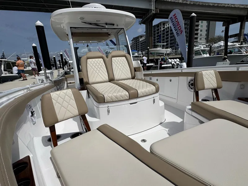 Slide: The Image of 2024 Everglades 315CC boat interior with beige and white seating at a marina. - 36