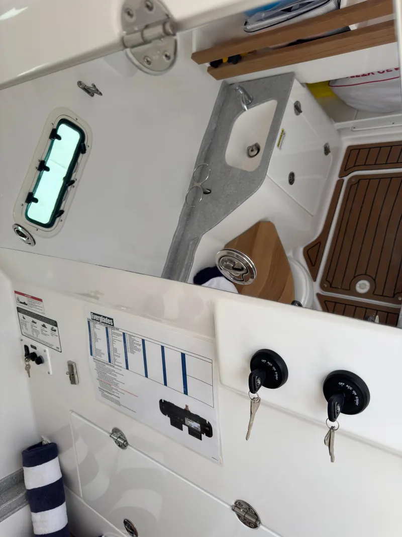 Slide: The Image of 2024 Everglades 315CC boat interior with sink, storage, and wooden flooring. - 43
