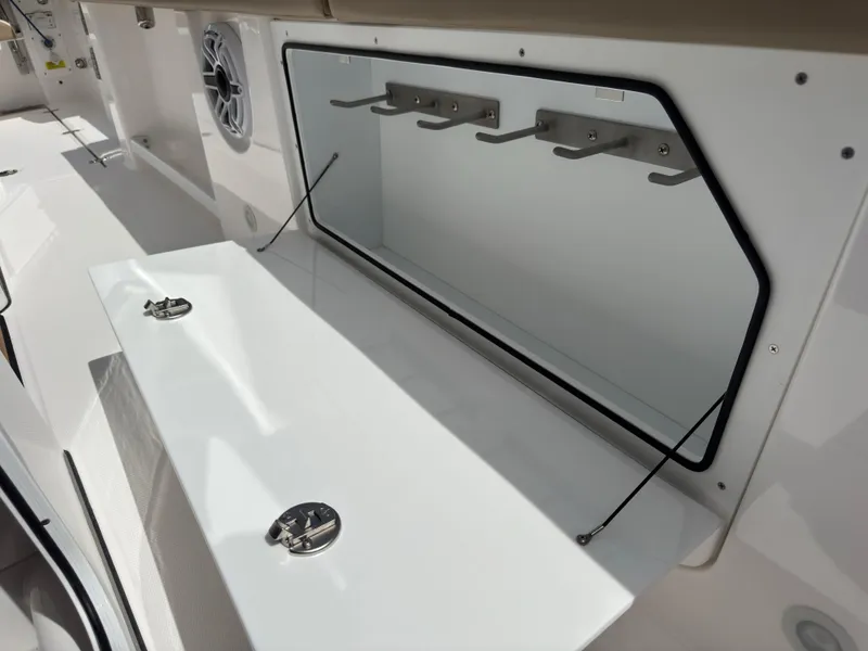Slide: The Image of 2024 Everglades 315CC boat storage compartment with open hatch and hooks. - 46