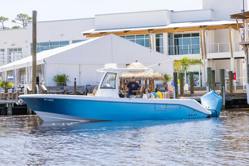 Slide: The Image of 2024 Everglades 315CC boat docked by a waterfront building, featuring a sleek blue design. - 6