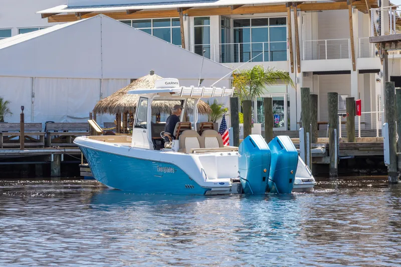 Slide: The Image of 2024 Everglades 315CC boat with dual engines docked near waterfront buildings. - 7