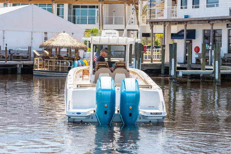 Slide: The Image of 2024 Everglades 315CC boat with dual engines docked in a marina setting. - 8