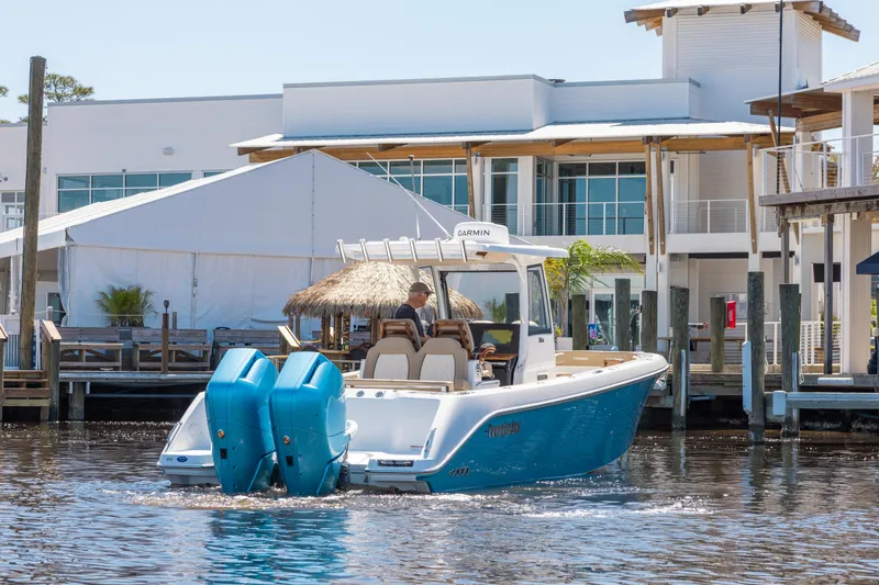 Slide: The Image of 2024 Everglades 315CC boat cruising near modern waterfront buildings. - 9