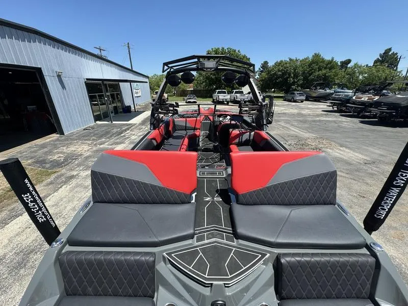 Slide: The Image of 2024 Tigé Z5 boat with red and gray interior, parked outdoors near a building. - 2