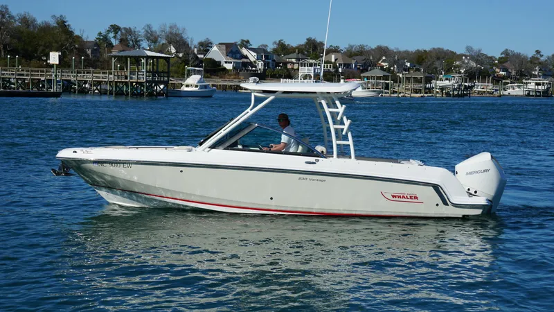 Slide: The Image of 2018 Boston Whaler 230 Vantage boat cruising on a calm lake near a residential area. - 9