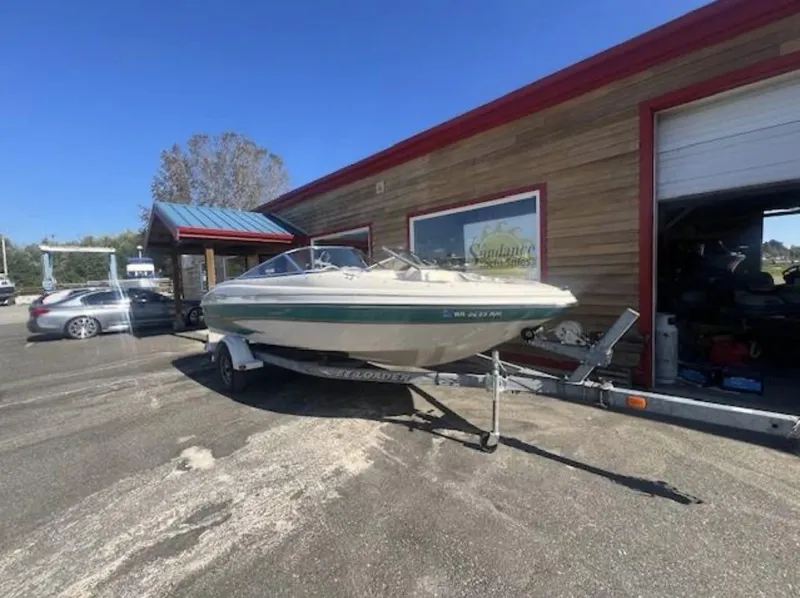 The Image of 2003 Glastron GX 185 boat on trailer outside a building under clear blue sky. - 1