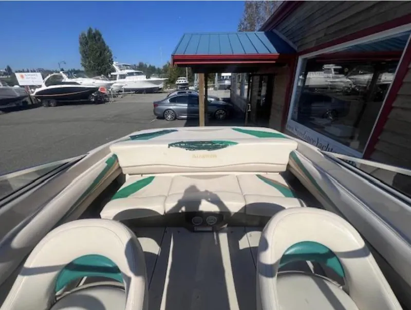Slide: The Image of 2003 Glastron GX 185 boat interior with white and green seating, parked near a marina. - 5