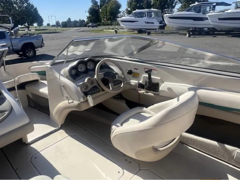 Slide: The Image of 2003 Glastron GX 185 boat interior with steering wheel and dashboard, parked outdoors. - 6