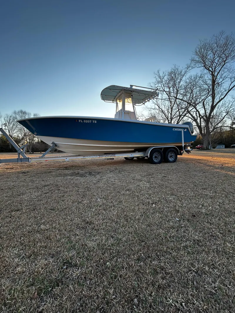 Slide: The Image of 2015 Contender 25 Tournament boat on trailer, parked on grass under clear sky. - 35