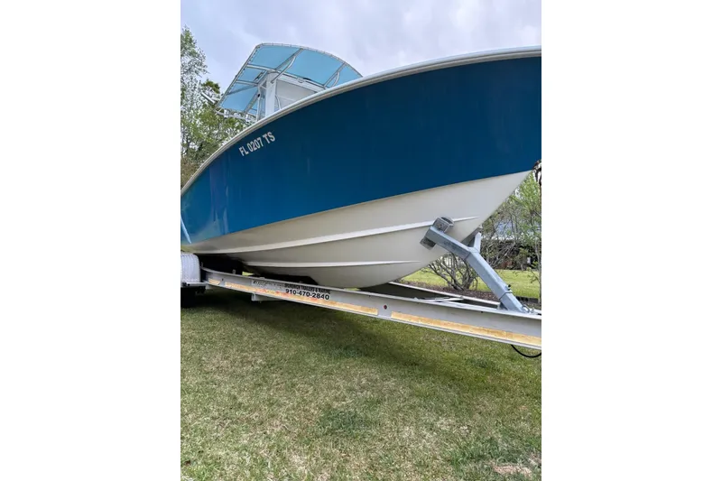 Slide: The Image of 2015 Contender 25 Tournament boat on trailer, blue hull, parked on grass. - 44