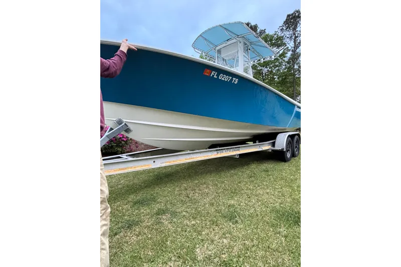 Slide: The Image of 2015 Contender 25 Tournament boat on trailer, blue hull, parked on grass. - 45
