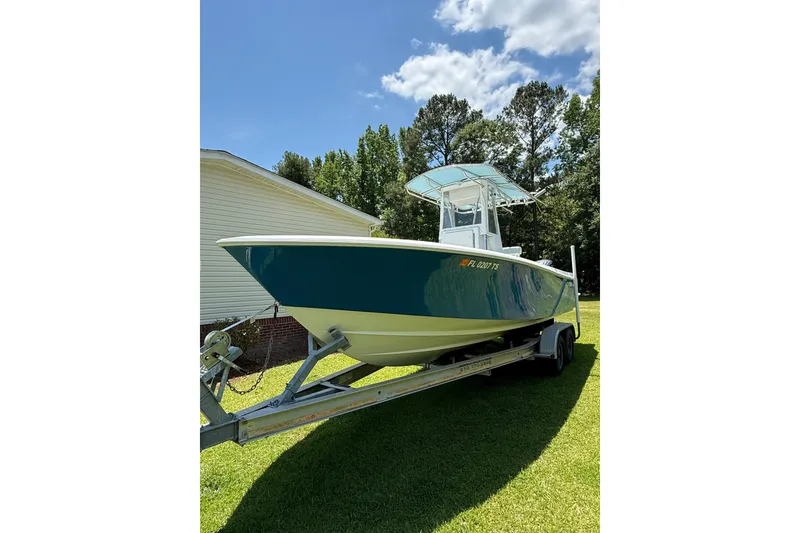 Slide: The Image of 2015 Contender 25 Tournament boat on trailer, parked on grass under blue sky. - 58