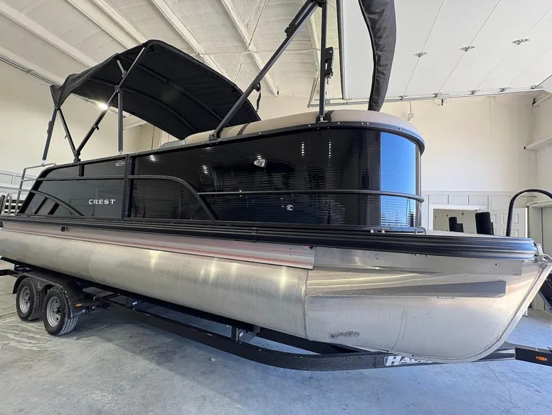 Slide: The Image of 2025 Crest Classic 220 pontoon boat on trailer in showroom setting. - 5