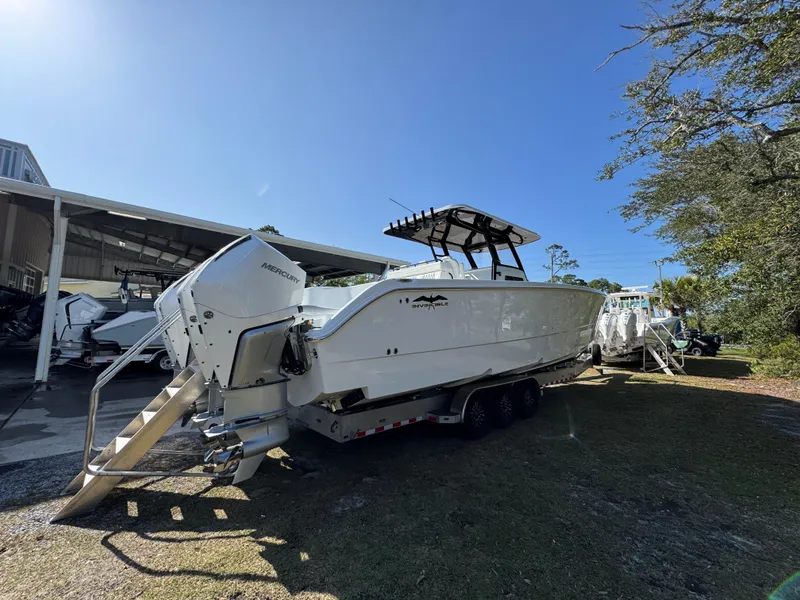 Slide: The Image of 2025 Invincible 38 Catamaran on trailer, parked outdoors under clear blue sky. - 10