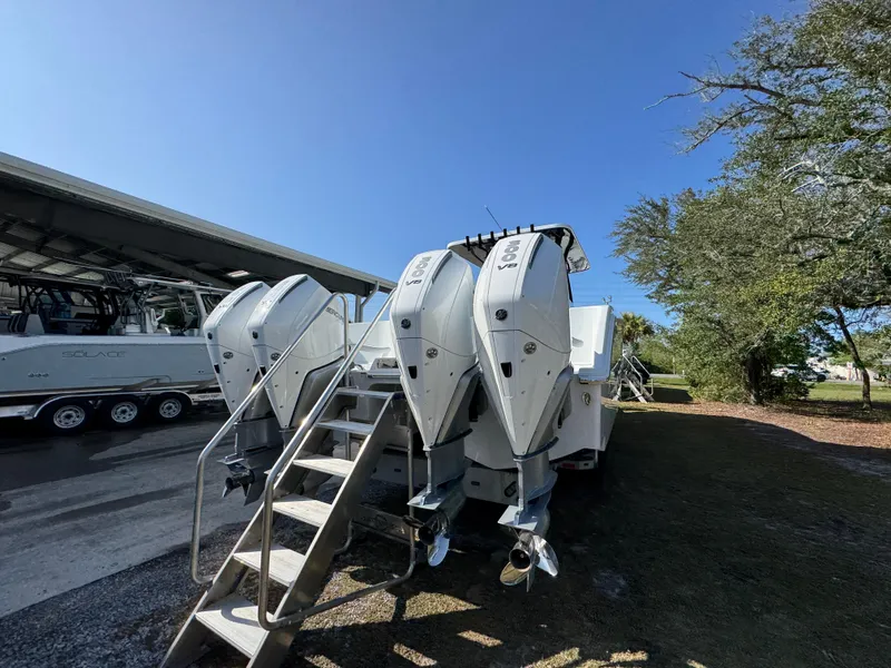 Slide: The Image of 2025 Invincible 38 Catamaran with triple outboard engines, parked outdoors under clear sky. - 12