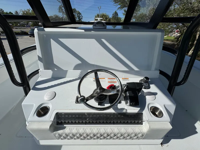 Slide: The Image of 2025 Invincible 38 Catamaran helm with steering wheel and controls, under clear blue sky. - 26