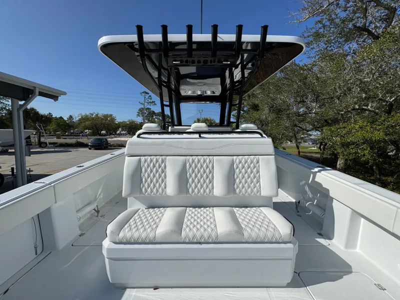 Slide: The Image of 2025 Invincible 38 Catamaran with white cushioned seating and T-top in a sunny outdoor setting. - 28