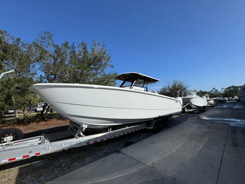 Slide: The Image of 2025 Invincible 38 Catamaran on trailer, parked outdoors under clear blue sky. - 3