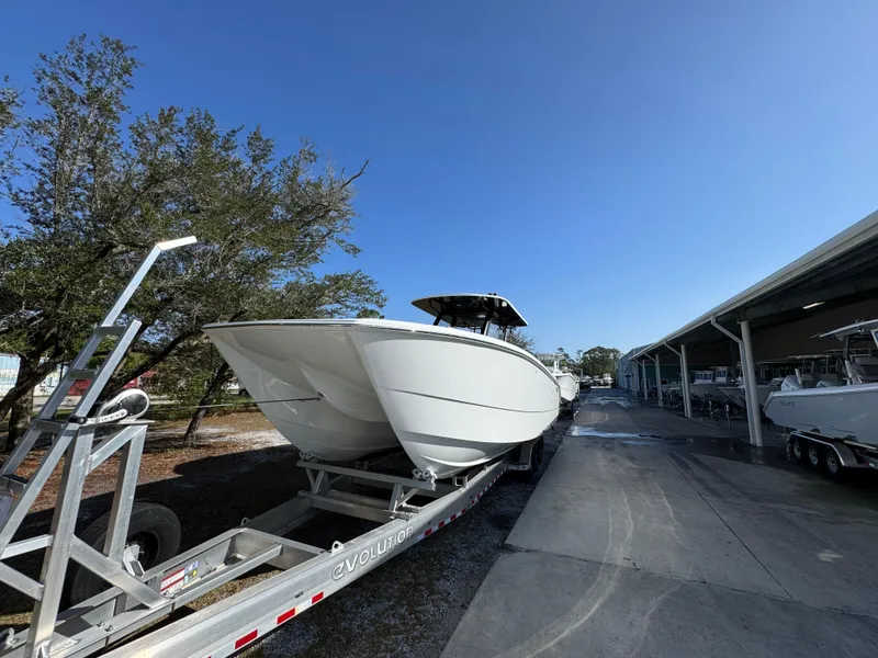 Slide: The Image of 2025 Invincible 38 Catamaran on trailer, parked outdoors under clear blue sky. - 4