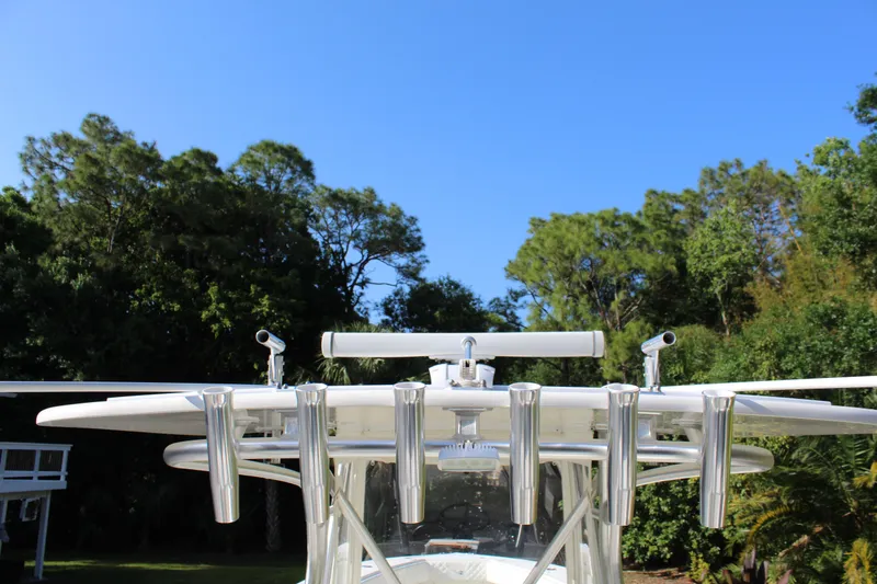 Slide: The Image of 2016 SeaVee 340Z boat with rod holders against a clear blue sky and lush greenery. - 15