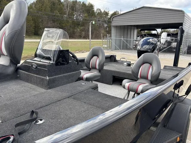 Slide: The Image of 2016 Ranger VS1680 boat with gray interior and dual seats, parked near a metal shed. - 6