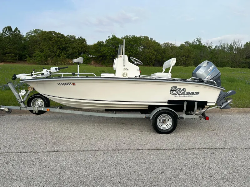 Slide: The Image of 2006 Carolina Skiff SEA CHASER boat on trailer, parked on roadside with grassy background. - 45