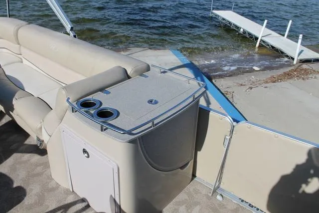 Slide: The Image of 2011 Harris 250 SL Grand Mariner boat interior with seating and cup holders by the water. - 11