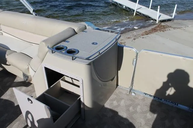 Slide: The Image of 2011 Harris 250 SL Grand Mariner boat interior with storage and cup holders by the water. - 12
