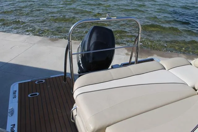Slide: The Image of 2011 Harris 250 SL Grand Mariner boat with cushioned seating and outboard motor by the water. - 16