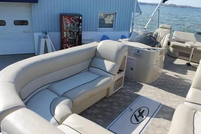 Slide: The Image of 2011 Harris 250 SL Grand Mariner pontoon boat with beige seating, docked by a lakeside building. - 6