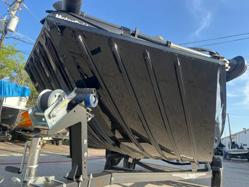 Slide: The Image of 2022 Lowe Legacy boat with Mercury outboard motor on a trailer, parked outdoors. - 15