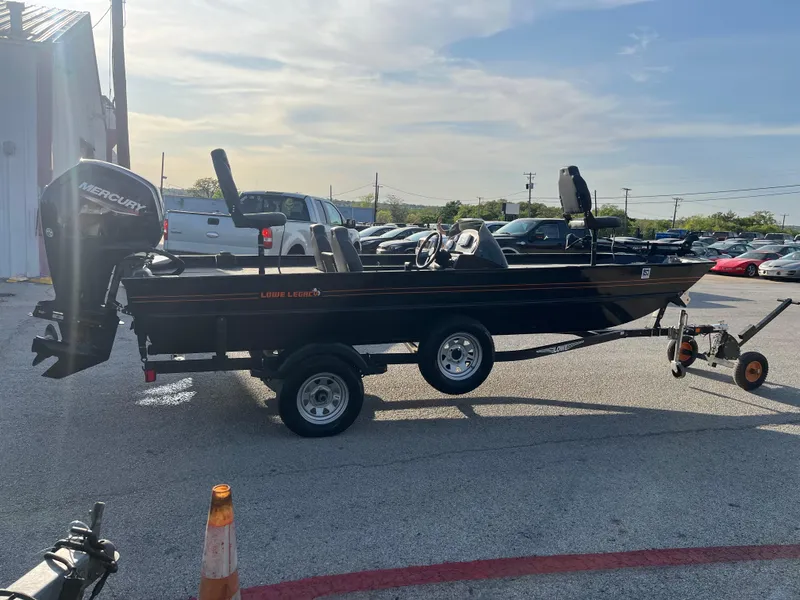 Slide: The Image of 2022 Lowe Legacy boat with Mercury outboard motor, parked on a trailer in a lot. - 18