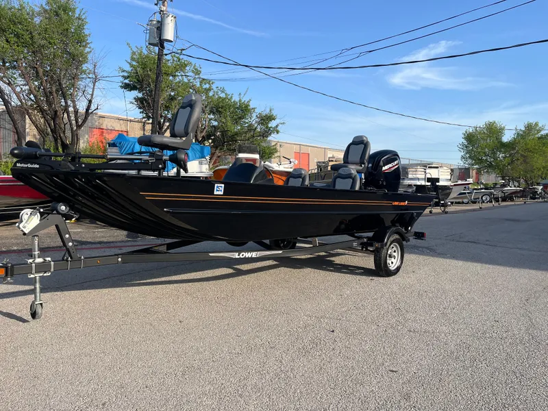 Slide: The Image of 2022 Lowe Legacy boat on trailer, parked outdoors, with trees and buildings in the background. - 22