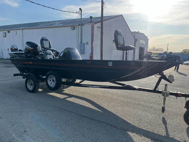 Slide: The Image of 2022 Lowe Legacy boat on trailer, parked outdoors near a warehouse. - 40