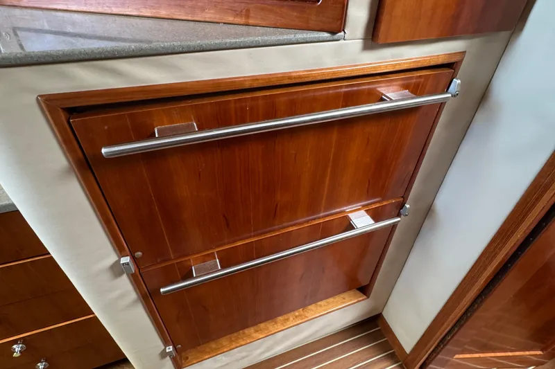 Slide: The Image of Wooden cabinetry with metal handles in a 2007 Albemarle 410 Express Fisherman boat interior. - 54